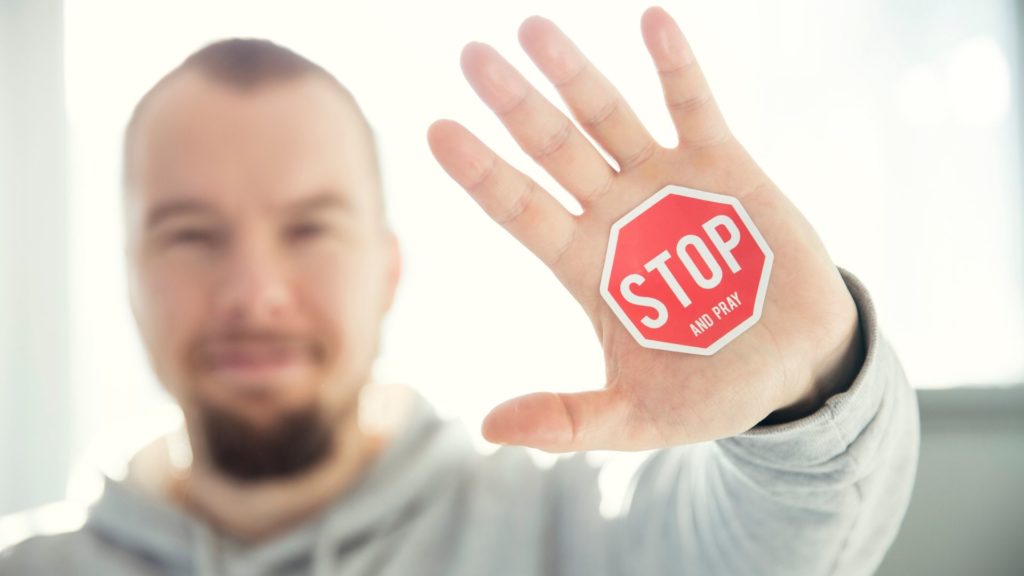 persona mostrando la palma de la mano, donde pone stop