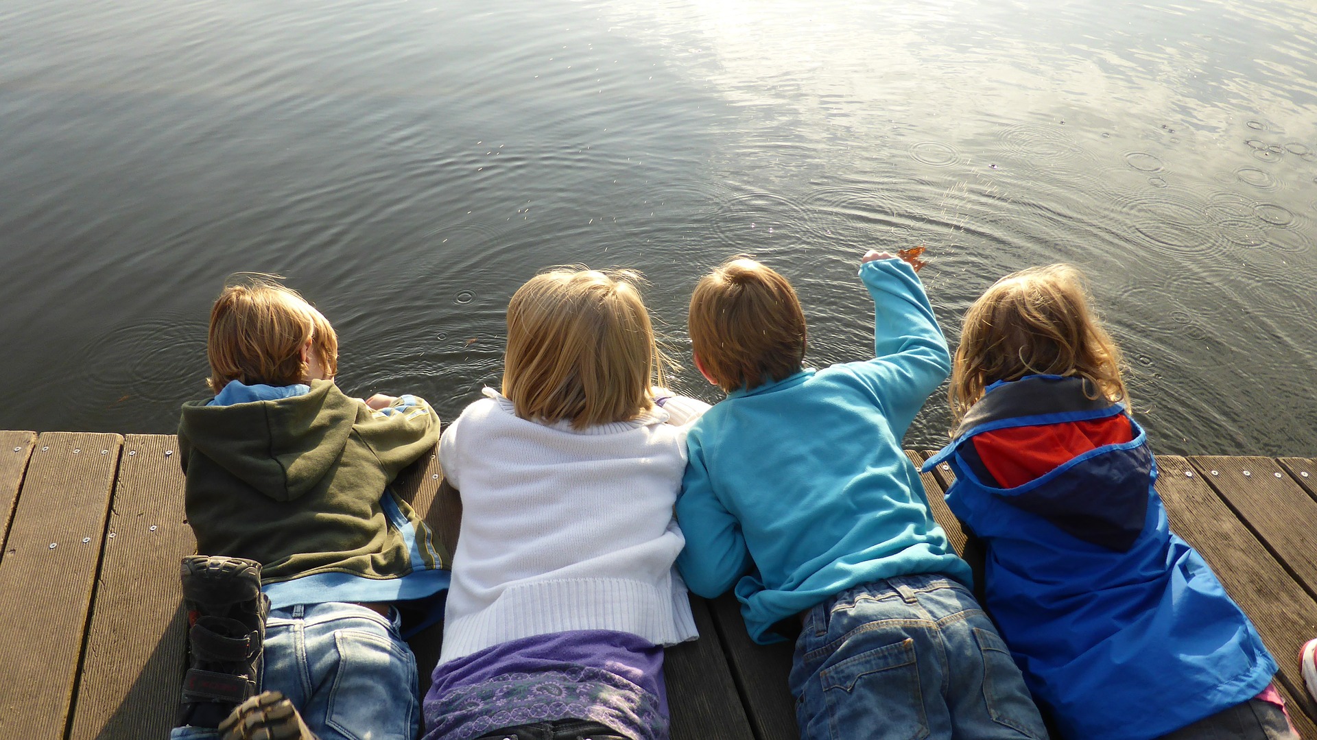 niños y niñas tumbados mirando un lago